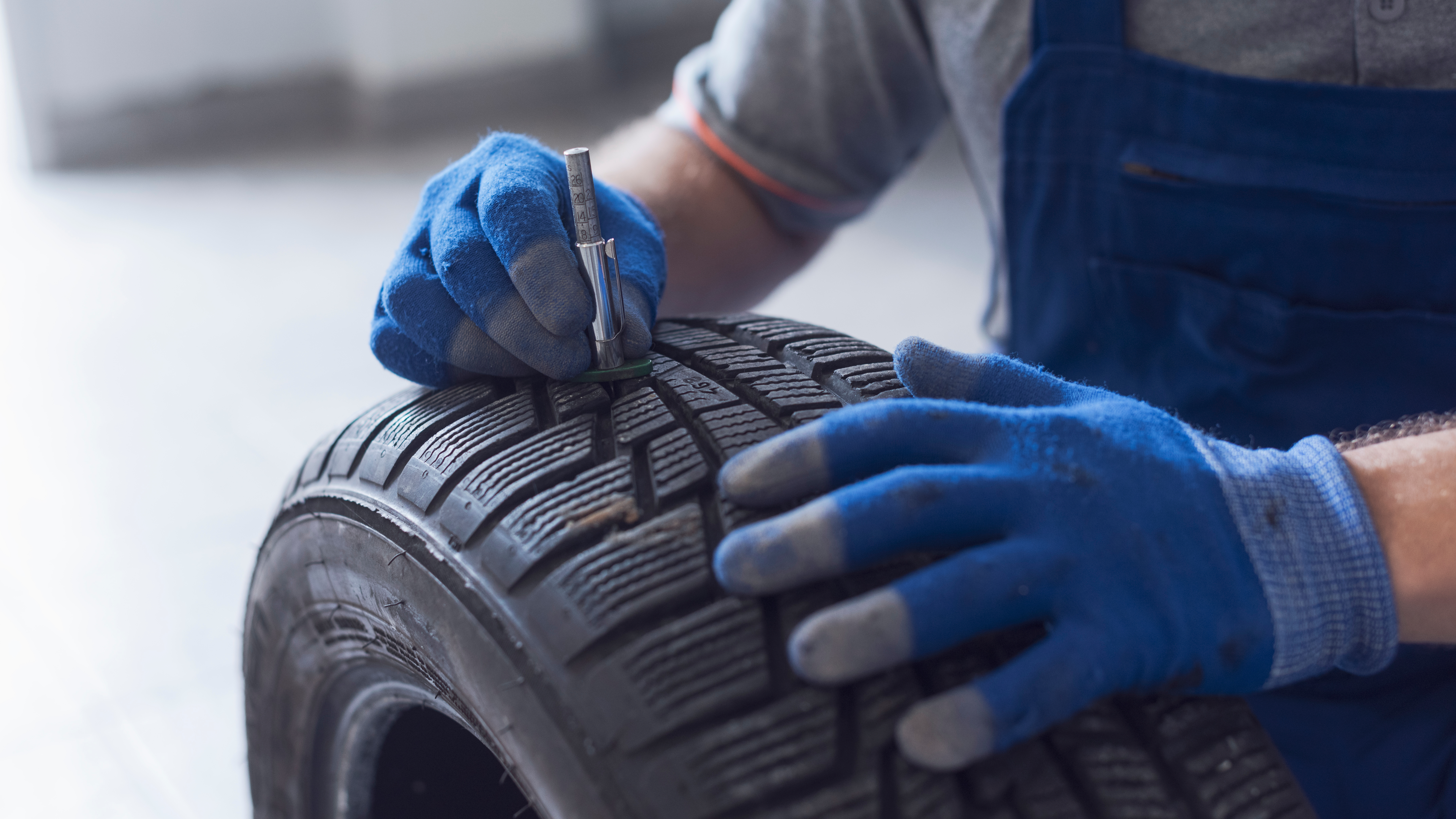 a mechanic measuring the tread depth of a tire
